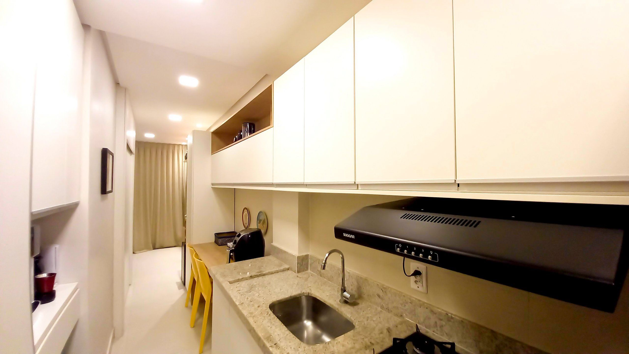 A modern kitchen with white cabinets, a stainless steel sink, and a black range hood.