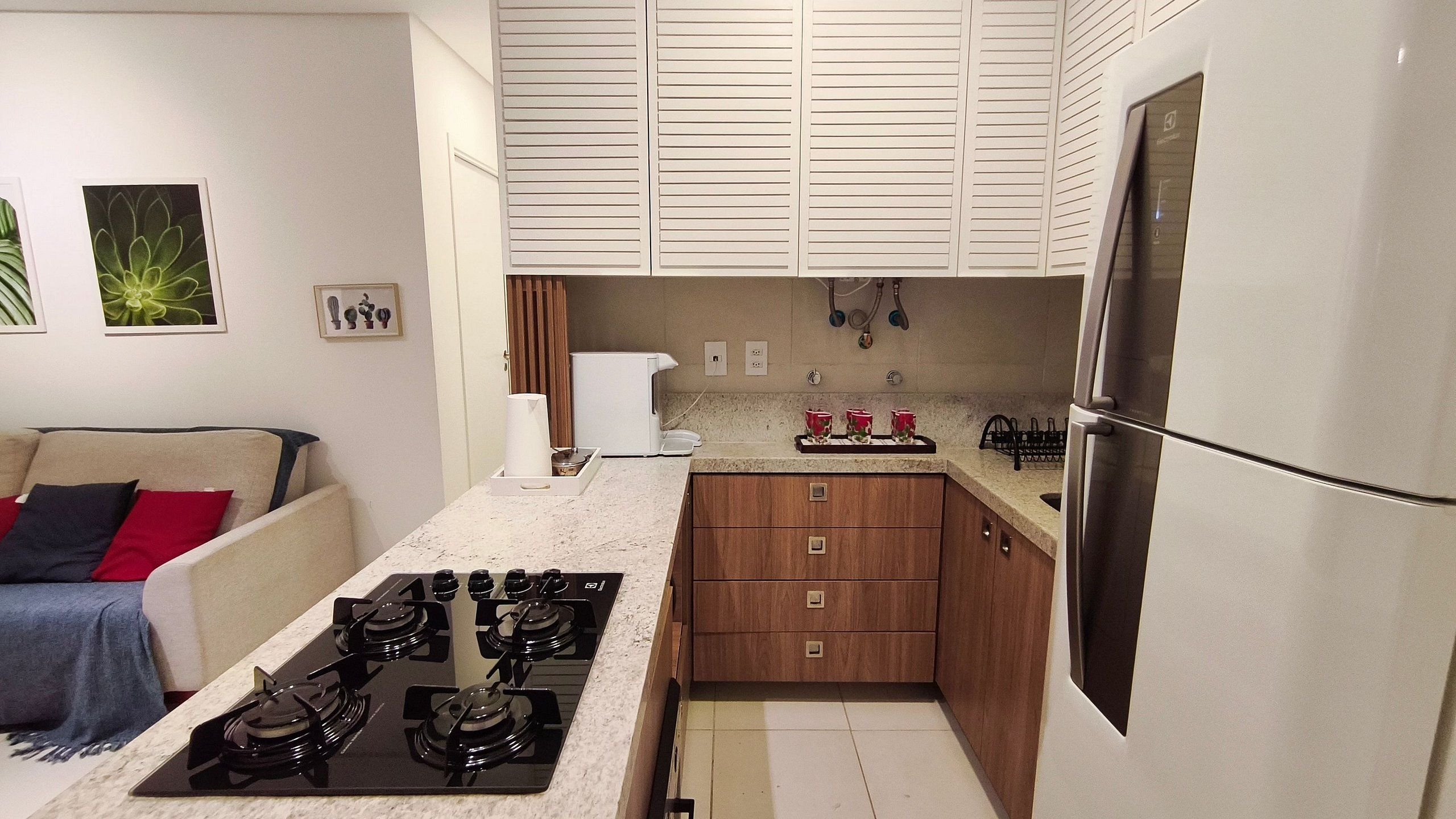 A compact kitchen with a gas stove, wooden cabinets, a refrigerator, and a countertop.