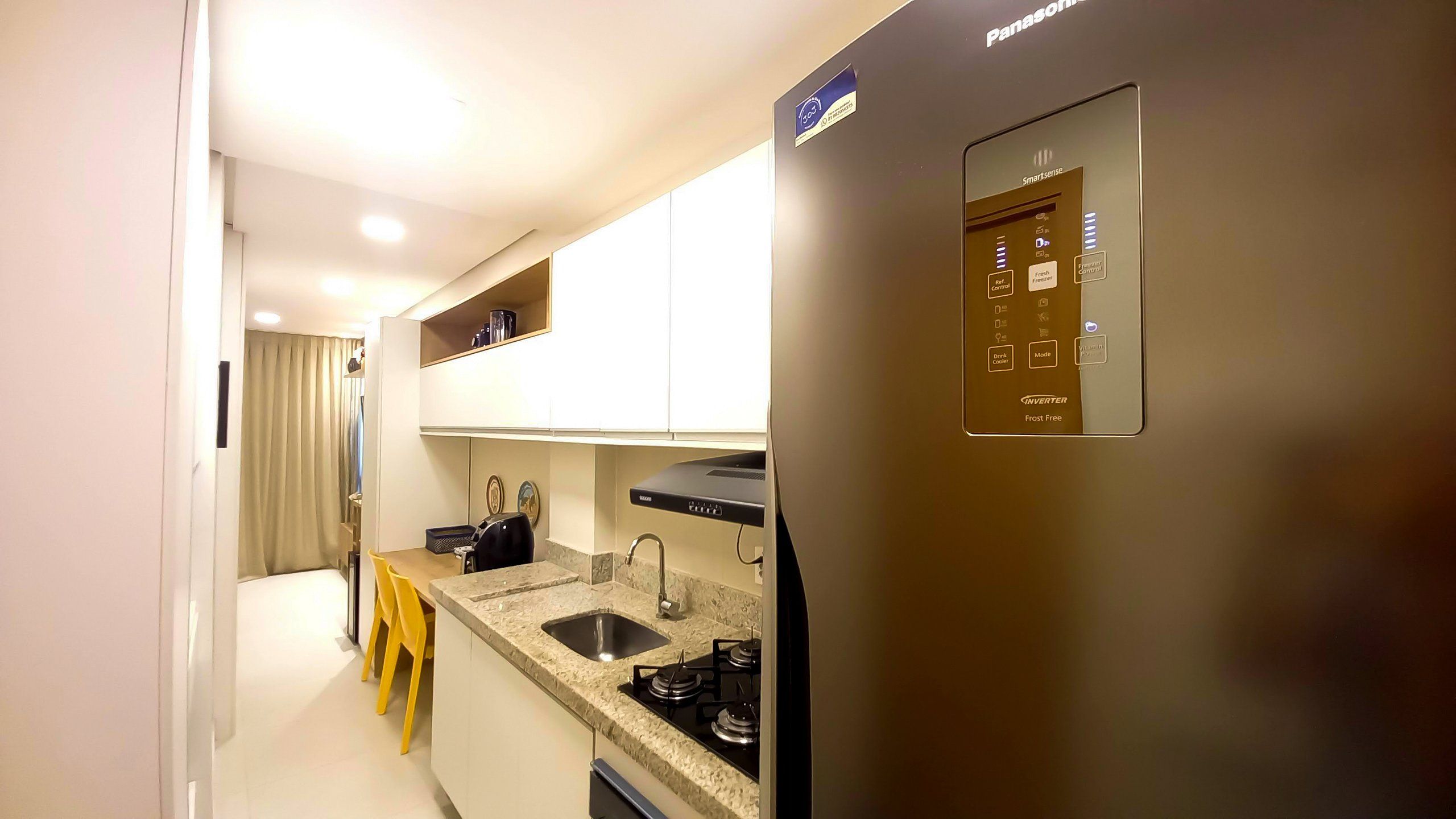 A modern kitchen with a built-in stove, a sink, and a refrigerator with a control panel.