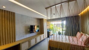 Een moderne hotelkamer met een televisie, een bed, een hangstoel en uitzicht op de omgeving.