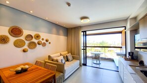 A modern living room with a sofa, dining table, and decorative wall art. - Lindos apartamentos no Eco Resort (Tamandaré)