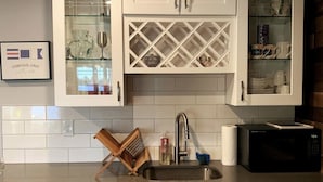 A kitchen with white cabinets, a stainless steel sink, a microwave, and a wooden drying rack. - Lakefront Apartment on Beautiful Lake Tapps, Spectacular Views (Bonney Lake)
