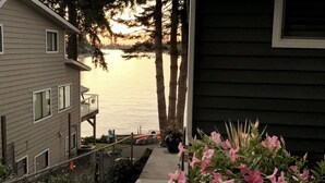A residential building with a view of a calm lake and tall trees in the background. - Lakefront Apartment on Beautiful Lake Tapps, Spectacular Views (Bonney Lake)