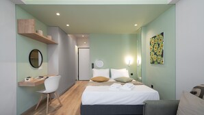 A modern hotel room with a bed, a desk, and a chair. There is a wall-mounted shelf with decorative items. - Kolokotroni Lofts Syntagma (Athens)