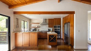 Una cocina moderna con armarios de madera, electrodomésticos de acero inoxidable y una estantería para vinos.