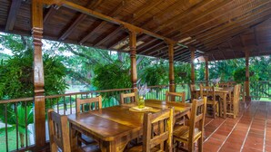 An outdoor wooden deck with a tiled floor, surrounded by lush greenery.