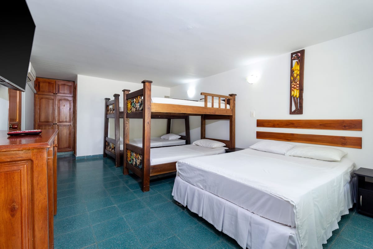 A room with bunk beds, a wooden dresser, and a bed with white bedding.