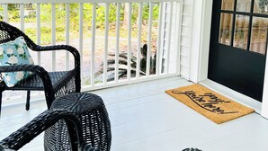 A porch with wicker chairs and a doormat. - Azalea Suite at The Mockingbird Inn (Ocean Springs)