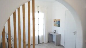 A room with a wooden slatted partition, a white door, a small table with a bottle, and a painting on the wall. - Spacious 2BR Flat, Pergola Veranda, 20m to Agios Prokopios Beach (Naxos)