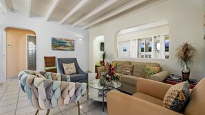 Un salon moderne avec un canapé, un fauteuil et une table basse. Un tableau est accroché au mur et une plante est posée sur le côté.