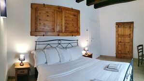 Une chambre à coucher avec un lit, deux lampes de chevet, une armoire en bois et une porte.
