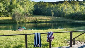 A wooden deck overlooking a calm lake with a boat docked on the shore.