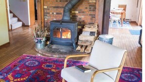 A cozy living room with a wood-burning stove, a patterned rug, and a comfortable chair.