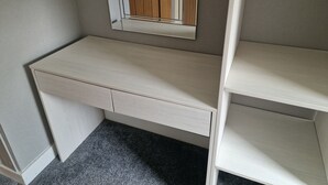 Un dormitorio con esquina, escritorio integrado, espejo y armario.