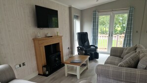 Una sala de estar con chimenea, televisor, sofá y sillón.