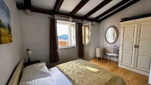 A bedroom with a bed, a window, a chair, a wardrobe, and a mirror.