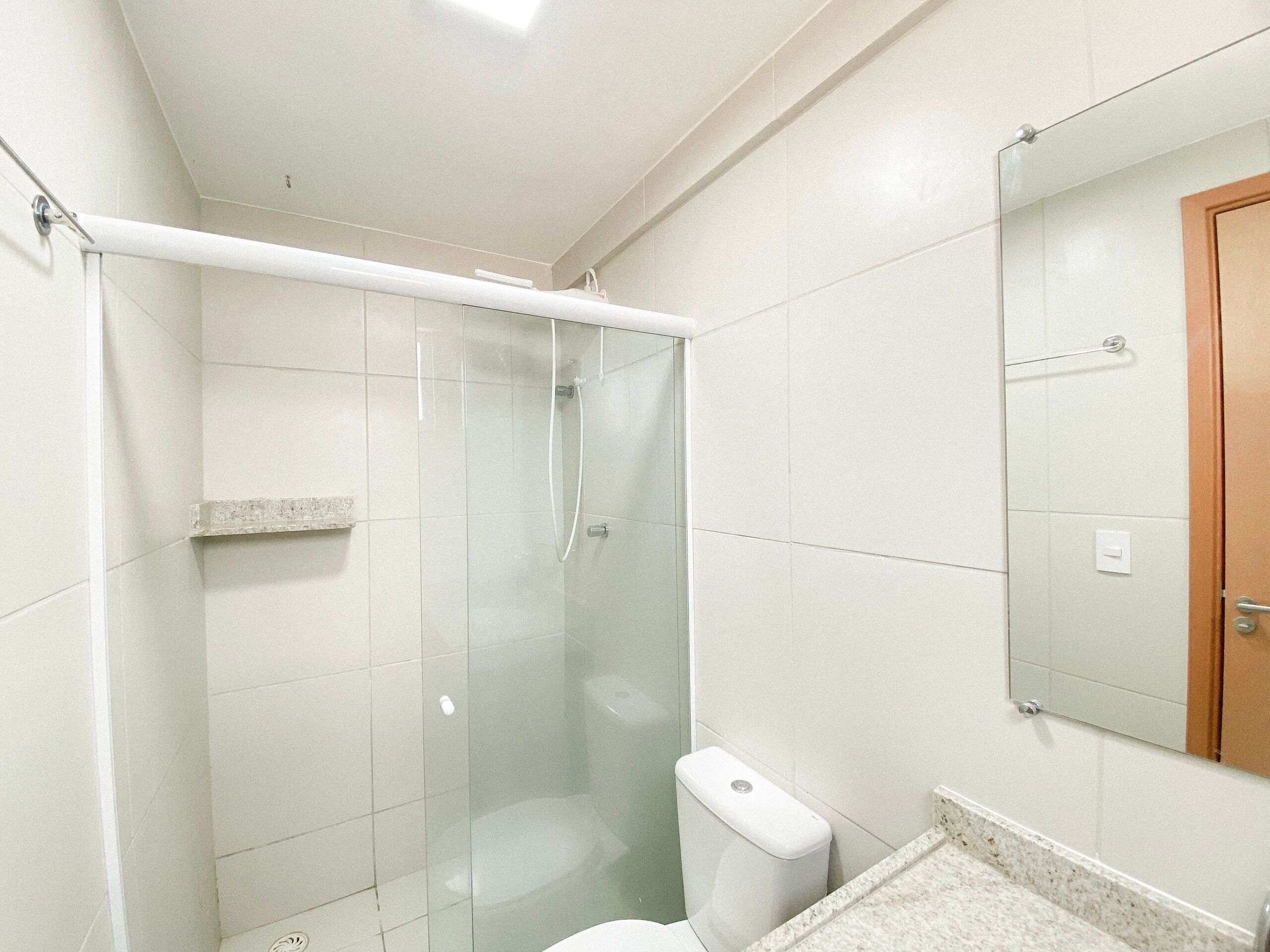 Un bagno con box doccia in vetro, un water e un lavandino con specchio soprastante.