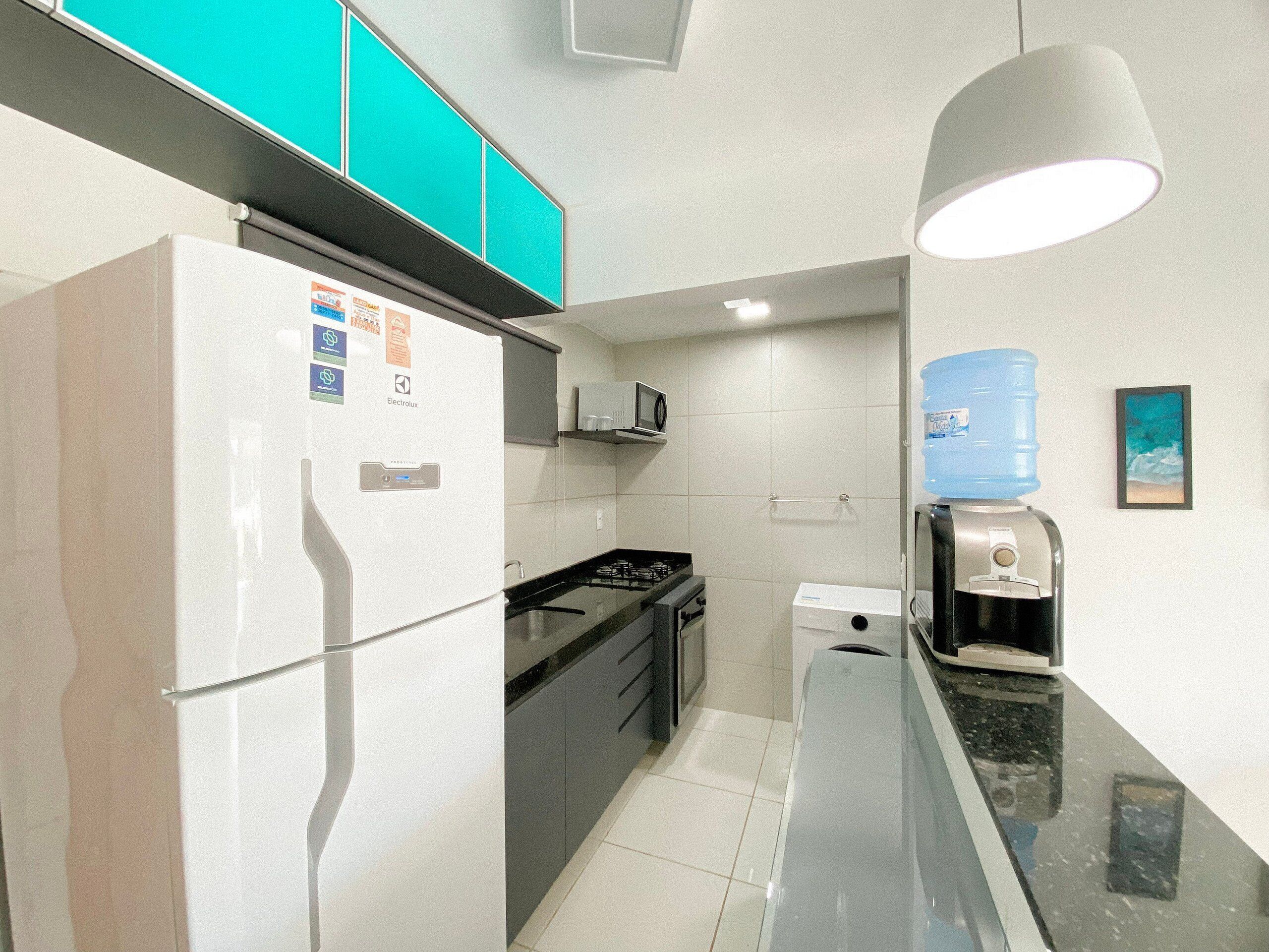 Cocina compacta con refrigerador, microondas, estufa y dispensador de agua.
