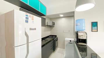 Cozinha compacta com geladeira, micro-ondas, fogão e bebedouro.