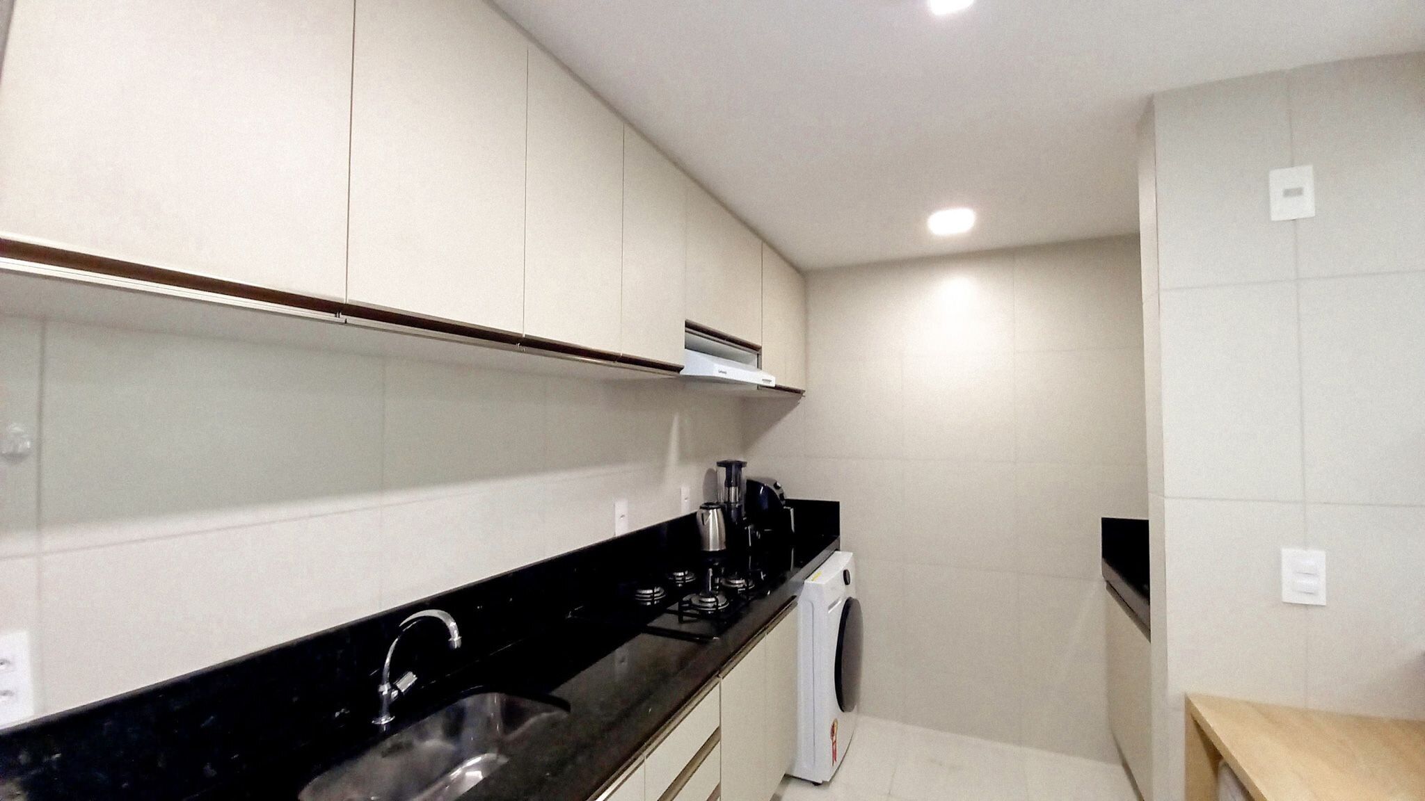 A compact kitchen with a black countertop, stainless steel sink, and a built-in oven.