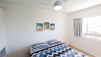 Un dormitorio con una cama, un ventilador de techo y tres cuadros en la pared.