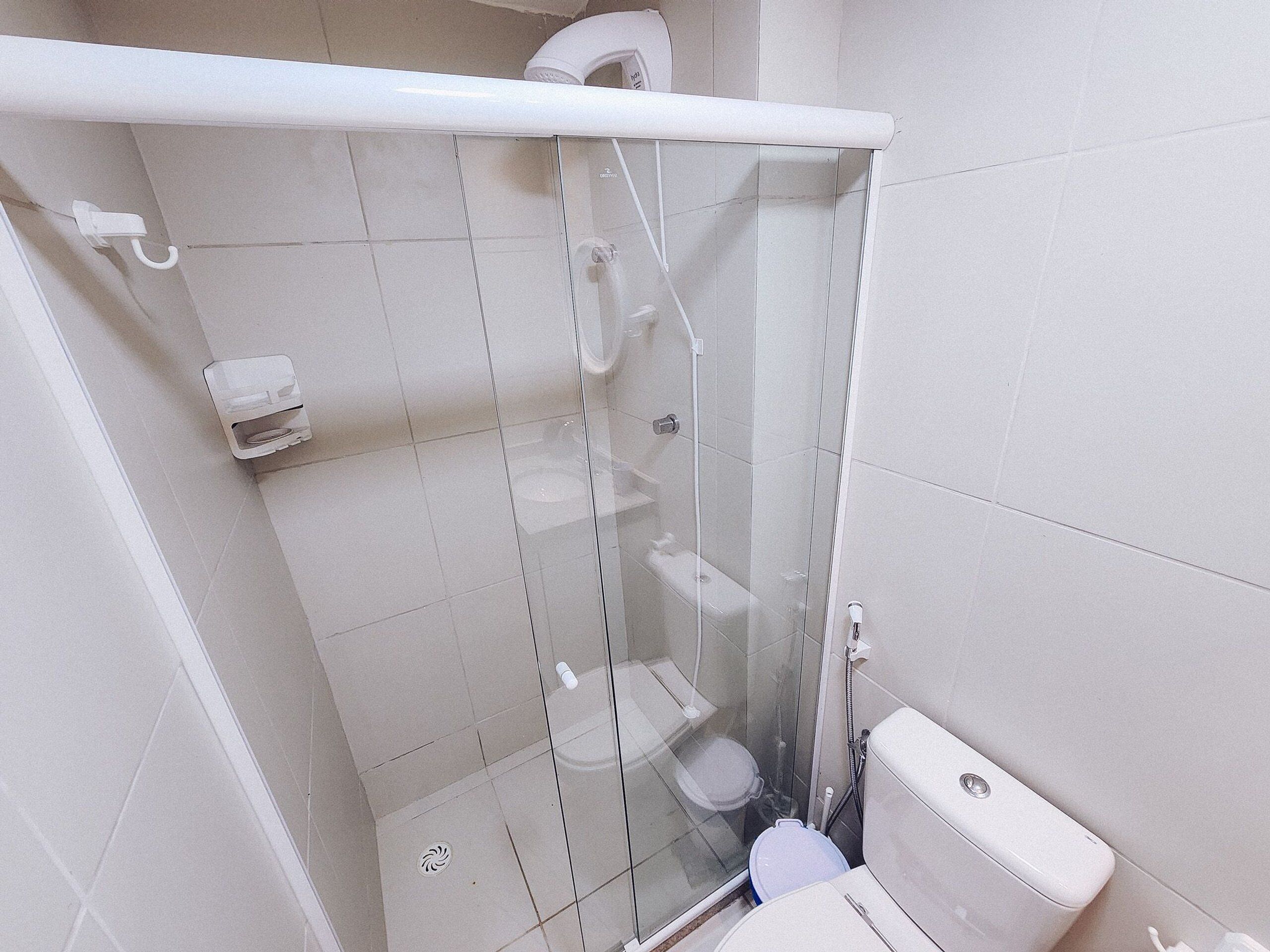 A small, modern bathroom with a glass-enclosed shower, a toilet, and a sink.