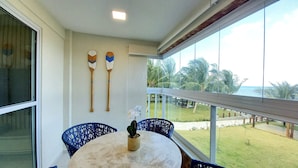 A balcony with a round table, two blue chairs, and two decorative paddles on the wall. - Lindos apartamentos no Porto Cayman (Tamandaré)