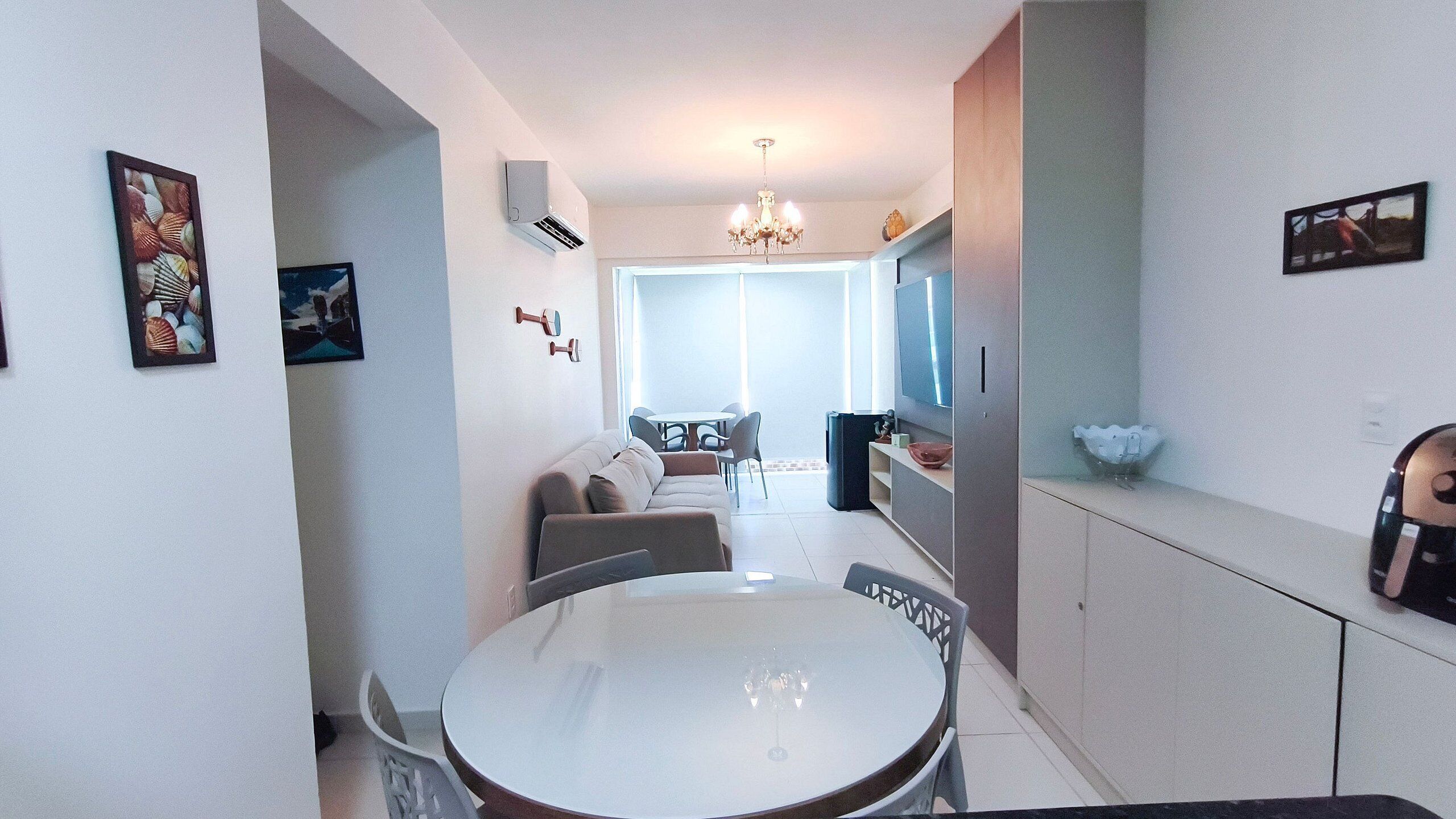 A modern kitchen with a dining area, featuring a round table, chairs, and a chandelier.
