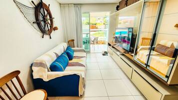 A living room with a sofa, chairs, a TV, and a large window.
