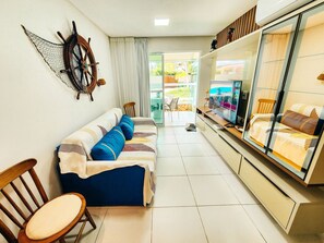 A living room with a sofa, chairs, a TV, and a large window.