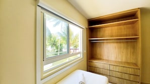 A bathroom with a window, wooden shelving, and a white sink. - Lindos apartamentos no Porto Cayman (Tamandaré)