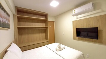 Habitación de hotel con cama, armario de madera, televisor de pantalla plana en la pared y aire acondicionado.