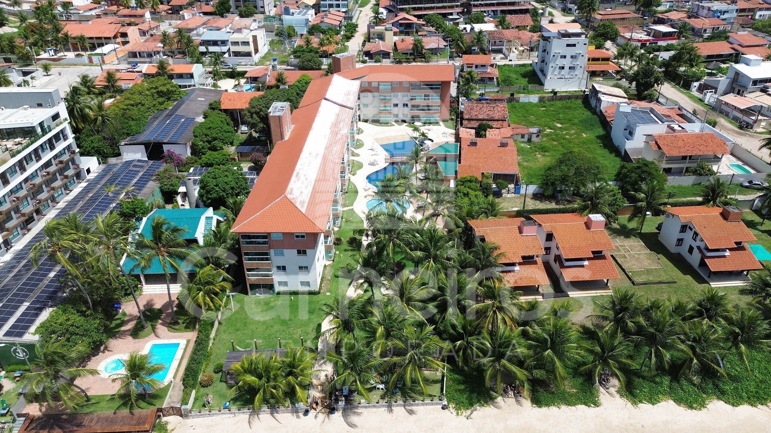 A resort with multiple buildings, a pool, and palm trees.