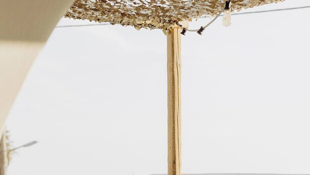 Een moderne zithoek buiten, met een bank, twee kleine tafels en een decoratieve lamp.