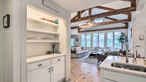 Une cuisine avec des meubles blancs, un plancher en bois et une grande fenêtre.