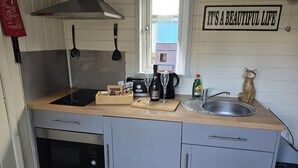 A compact kitchen with a stainless steel sink, a toaster, a wine bottle, and a cat figurine. - Glamping Hut - Sleeps 2, hot tub & Parking (Welshpool)