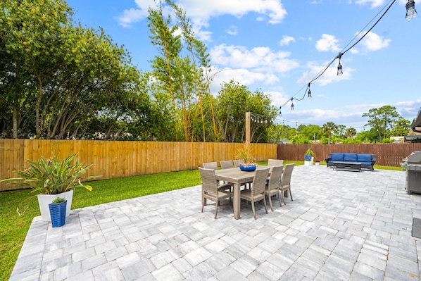 A patio with a table and chairs, a blue sofa, and a barbecue grill.
