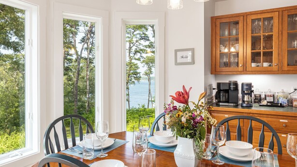 A dining area with a view of the sea, a wooden table set with plates and glasses, and a coffee maker on the counter. - A View Fit for Royalty!
Top Compliments:  so clean! fab hot tub! best view! (Tisbury)