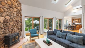 A spacious living area with a stone wall, a fireplace, a sofa, and a dining area visible through large windows. - A View Fit for Royalty!
Top Compliments:  so clean! fab hot tub! best view! (Tisbury)