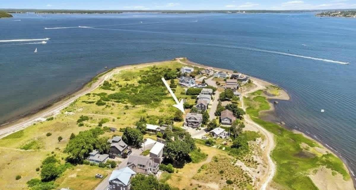 Vista aérea de una zona residencial costera con casas, áreas verdes y una playa.