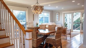 A dining area with wicker chairs, a wooden table, and a chandelier. - Luxury Waterfront Property 360 water views (Portsmouth)