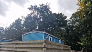 A blue building with a white trim, surrounded by a wooden fence. - Cabin - Sleeps 2 hot tub & Parking (Welshpool)