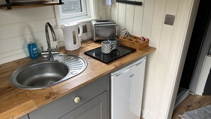 A compact kitchen with a sink, a toaster, a kettle, and a coffee maker on a wooden countertop. - Cabin - Sleeps 2 hot tub & Parking (Welshpool)