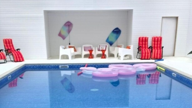 An indoor swimming pool with clear blue water, surrounded by red and white lounge chairs. - Cabin - Sleeps 2 hot tub & Parking (Welshpool)