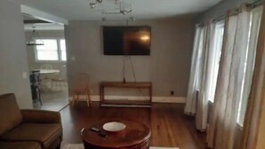 Un salon avec un canapé, une table basse et un téléviseur fixé au mur.