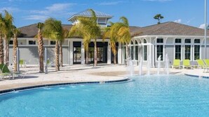 Une piscine bordée de palmiers et un bâtiment doté d’un toit en pente.