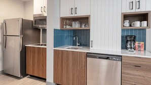 A modern kitchen with stainless steel appliances, wooden cabinets, and blue-tiled backsplash. - Staybridge Suites Federal Way - Seattle South by IHG (Federal Way)