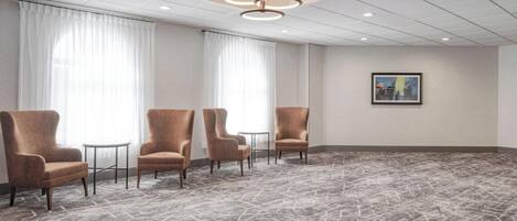 A conference room with four armchairs, a round table, and a painting on the wall.