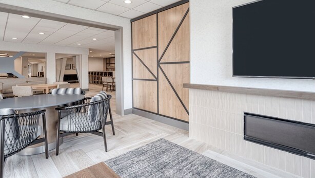 A modern living room with a large TV, a fireplace, and a dining area with a round table and chairs. - Staybridge Suites Federal Way - Seattle South by IHG (Federal Way)