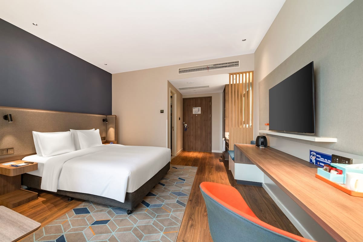 Ein Hotelzimmer mit Bett, Nachttisch, Fernseher und einem Schreibtisch.